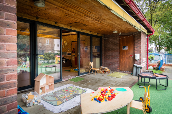 Glass doors opening from a community centre nursery to an outdoors play area. 